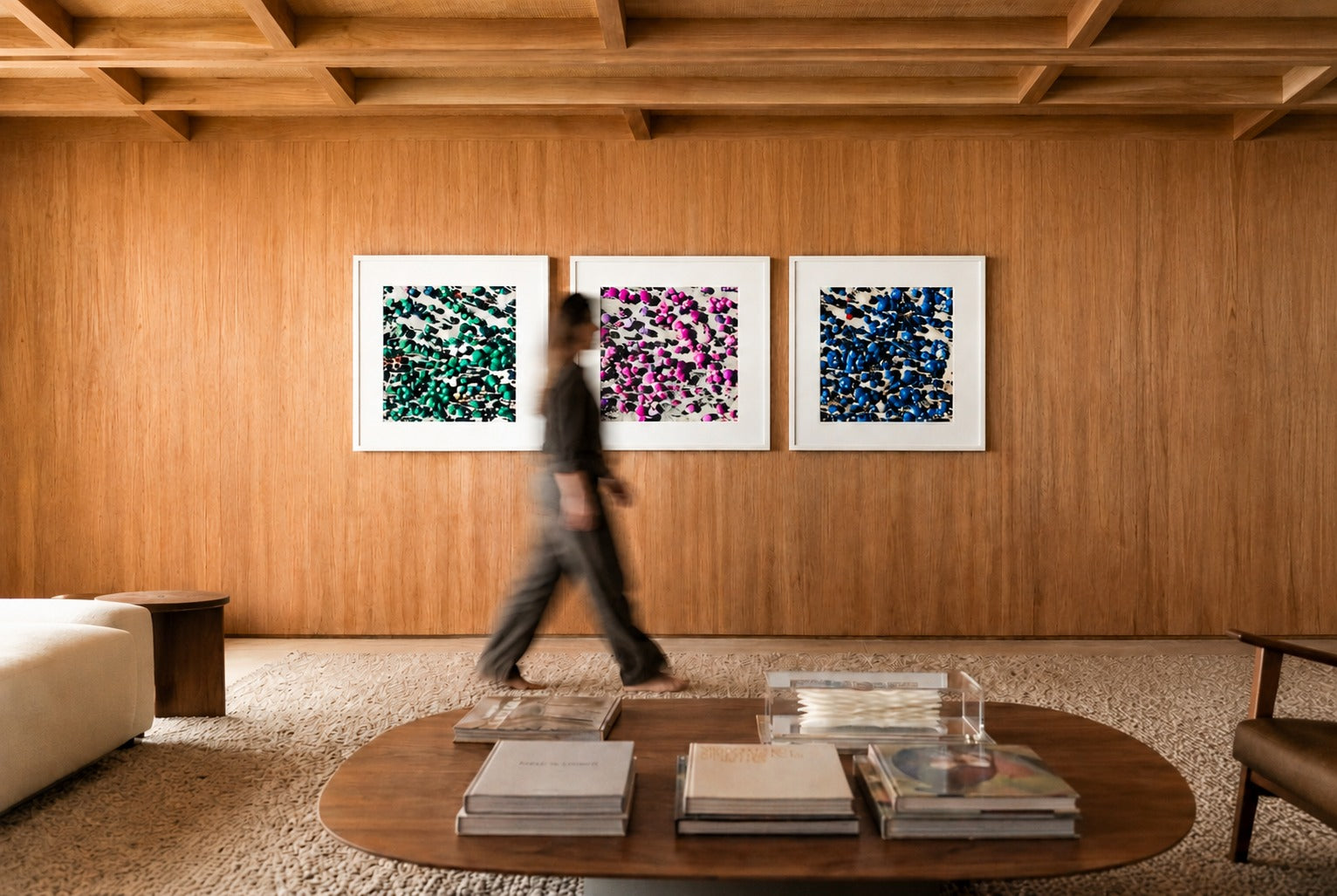 Três quadros Fine Art emoldurados em branco numa parede de madeira, com sofá e mesa de centro